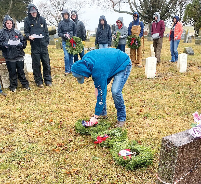 Pictured above, at left, Atticus Bertolino places a wreath to represent a branch of military during the opening ceremony.