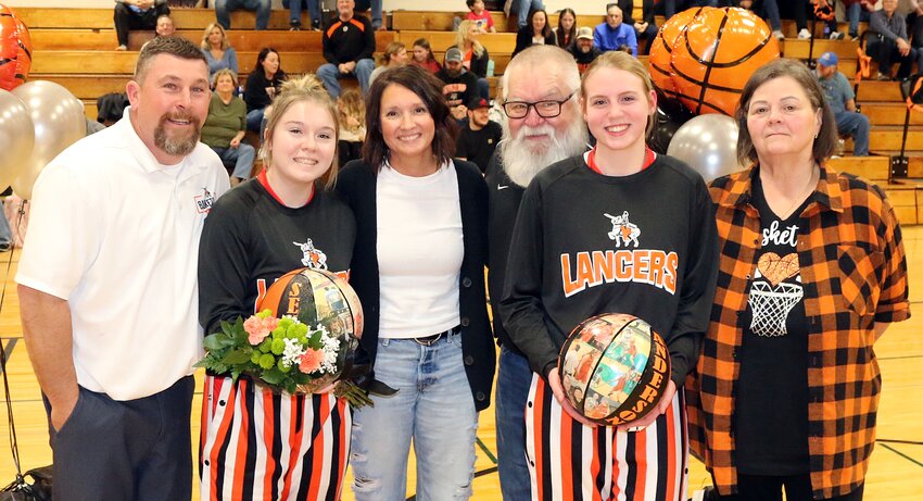 The Lincolnwood-Morrisonville girls basketball program honored two four-year players on senior night on Thursday, Feb. 8, prior to the Lady Lancers&rsquo; game against Mt. Olive in Raymond. From the left are Taryn Millburg, with parents Justin and Beth Millburg, and Chelsie Anderson, with parents George and Vickie Anderson.
