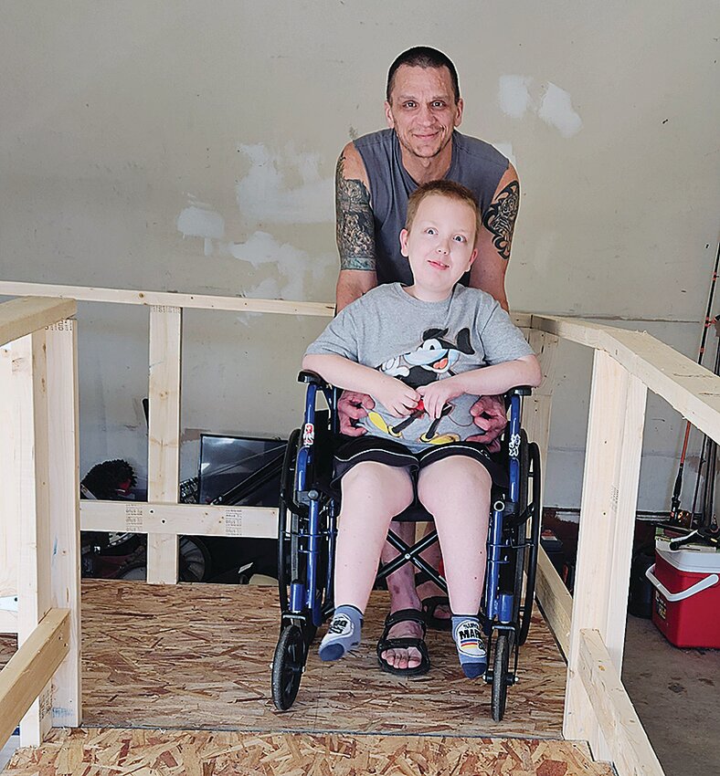 Michael Bryant and his son, Grant, try out the new ramp in their garage. The ramp was built by local volunteers, who spent their Saturday volunteering at the Bryant's home