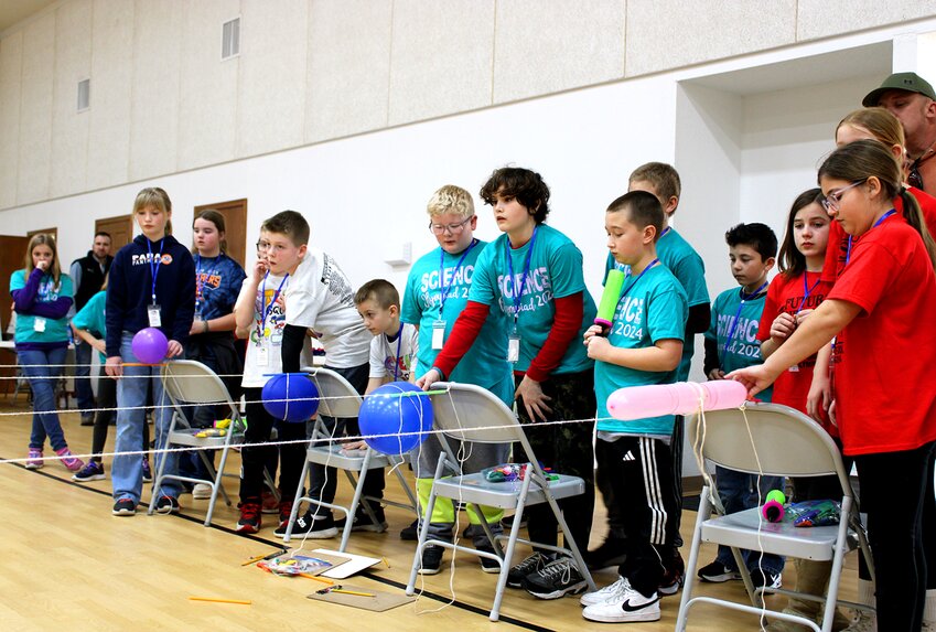 Pictured above, teams from the four schools prepare for the &lsquo;Balloon Racer&rsquo; event, where each team of students quickly constructed a balloon-powered device to launch a straw down the string, in hopes of going the furthest distance.