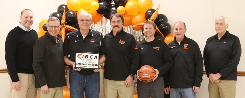 Representatives of the Illinois Basketball Coaches Association Steve Dilley and Steve Allen were on hand at the Raymond KC Hall on Friday, Feb. 16, to present the Lincolnwood boys basketball program with a plaque honoring the Lancers' 1,000th win, which happened on Jan. 2, 2024, against Mt. Pulaski. Lincolnwood coaches, pictured above, from the left, are Courtney Murphy (2000-2006, 110 wins); Craig Davelis (1992-1999, 128 wins), Mike Meisner (1979-1985, 75 wins), Steve Dilley, Matt Millburg (2012 to present, 195 wins as of Feb. 20), Steve Vance (2006-2010, 84 wins) and Steve Allen.