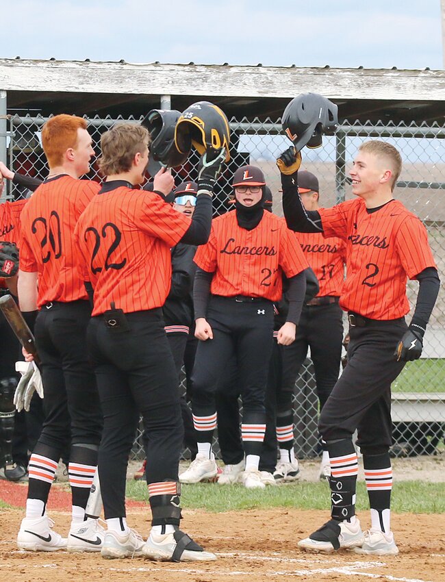 Lincolnwood junior Jonah Elvidge (#2) celebrates at home plate with teammates Lance Weitekamp (#20) and Mason Tryon (#22) after his two-run home run against Auburn on Friday, April 5, in Raymond. The homer cut the Trojans' lead to 3-2 at the time, but Auburn survived that rally and