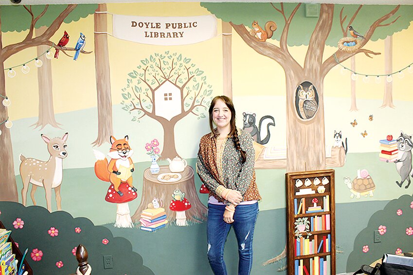 Artist Abbi McKinnie of Taylorville stands before the completed version of her biggest project yet, the mural that is now on display at Doyle Public Library in Raymond. McKinnie showed off the mural on Tuesday, April 23.