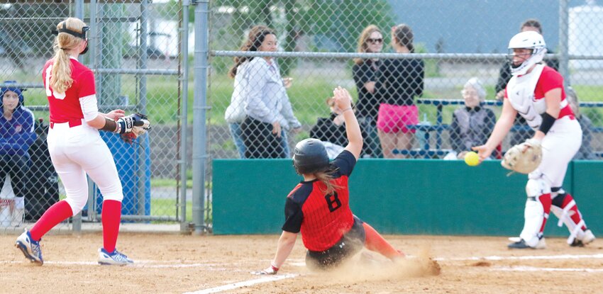 Lincolnwood senior Taryn Millburg slides safely into home plate before Pawnee catcher Makenna Corrie can recover a wild pitch and make the throw back to pitcher Haley Maretti during the regional semifinal game on Tuesday, May 14, in Raymond. The run was one of five the Lancers scored in the inning, but that only slightly cut into the Indians&rsquo; 12-0 lead at the time. Pawnee went on to win the game 19-5 to advance to the regional championship game on Saturday, May 18, at 11 a.m. against Carrollton.