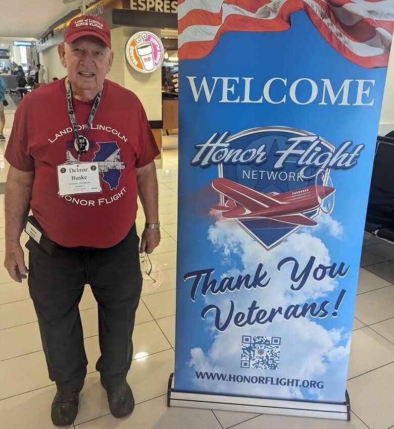 Litchfield resident Delmar Buske stands in front of a sign welcoming honor flight attendees.