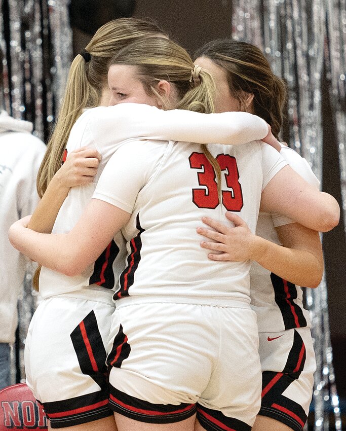 Lizzy Hill (#33) peeks back at the court as she and her fellow seniors, Natalie Brownback, Grace DeWerff and Becca Hill embrace near the end of Nokomis' game on Feb. 6. After two overtimes, the Lady Redskins scored a victory on senior night, beating Cowden-Herrick-Beecher City 61-54 to finish with a perfect 12-0 record at home.