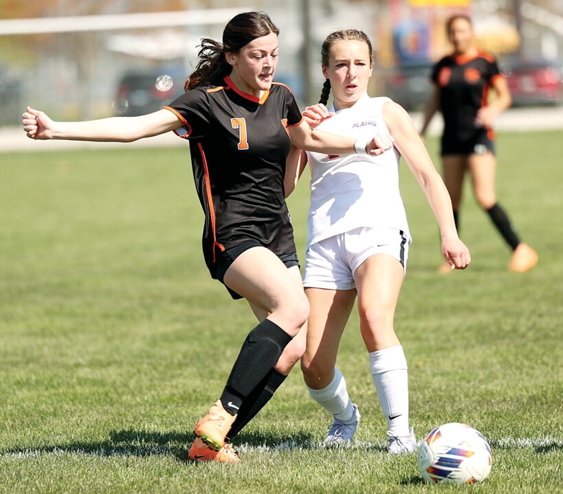 Hillsboro's Sloan Bertolino works to get the ball away from Pleasant Plains sophomore Callie Wagner during the Lady Hiltoppers home game on April 12. The undefeated Cardinals looked to be in mid-season form against Hillsboro as they scored ten times in the first half for a 10-0 victory.