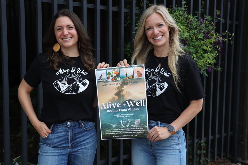 Elaine Welch (left) and Kay Boyer (right) hold up the poster for their upcoming documentary titled “Alive and Well – Healing from Within.” From the Heart Productions awarded the documentary with the “Hot Film in the Making” award and pledged financial support in the future with their Roy W. Dean Grant.