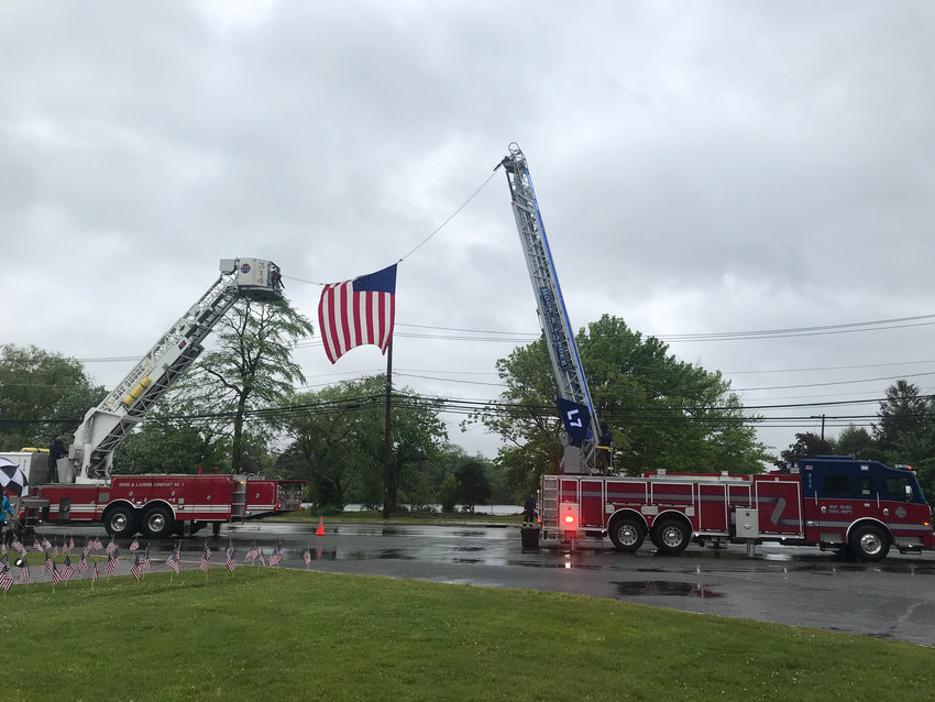 Bay Shore Fire Department’s Hook & Ladder Company No. 1 hang a U.S. flag between two fire trucks on Montauk Highway near the Canal.