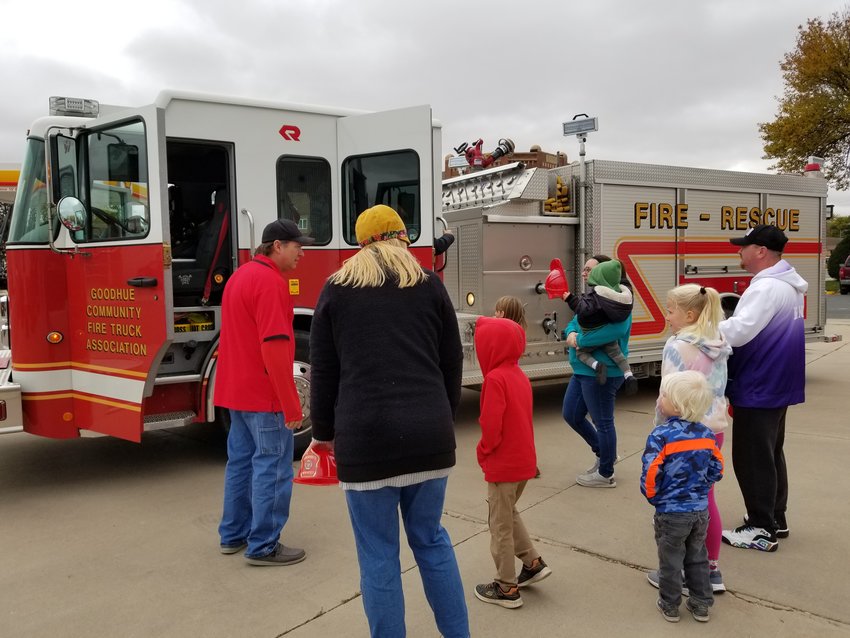 Goodhue Fire Department member, Jason Arendt, assists a group of parents and kids entering the fire truck for a ride around town.&nbsp; This educational experience was a popular attraction during the annual open house.