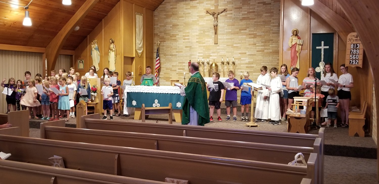 Father McCabe teaching songs to the children in the Church during Catholic Vacation Bible Camp.
