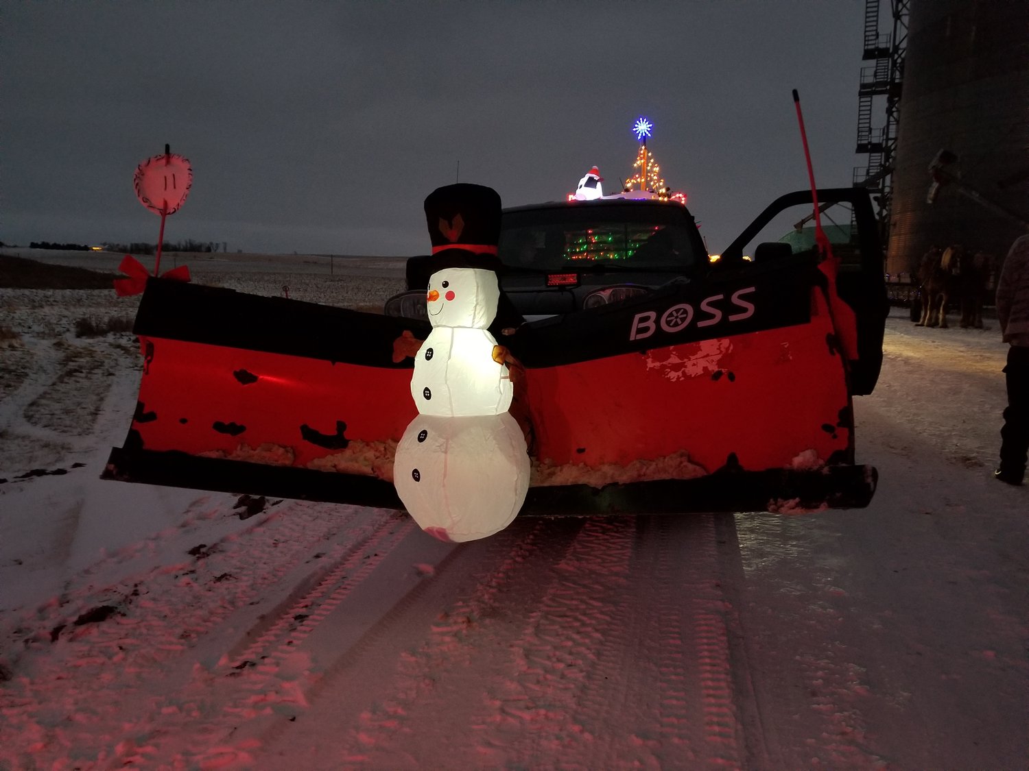 Jason Zemke pushed a troublesome snowman out of the way while cruising Bellechester with his float that carried a lighted tree and a skidloader with a shivering inflatable “driver”.   The entry won third place.