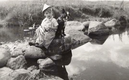 Emery and Buster in 1955 at the Wencel farm sitting on rocks in the middle fork of the Zumbro River.