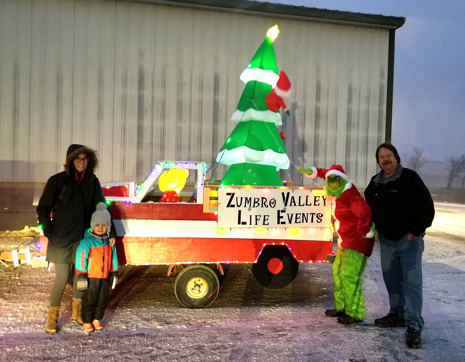 A Grinch in costume but not in spirit, Kristine Mischke is supported by friends and fellow non-profit representative, Roger Whipple (far right) during the Bellechester lighted Christmas parade.  Mischke is the secretary for the Zumbro Valley Life Events organization which offers monetary support for people going through life-changing events.  This is the first year the non-profit has had an entry in both the Bellechester and Zumbro Falls parades.