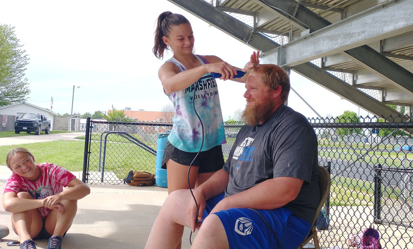 Senior Aaliyah Joiner puts the clippers to Jays track coach Roy Kaderlyat practice. Other teammates got to take some off the top as part of an incentive offered for earlier this season.