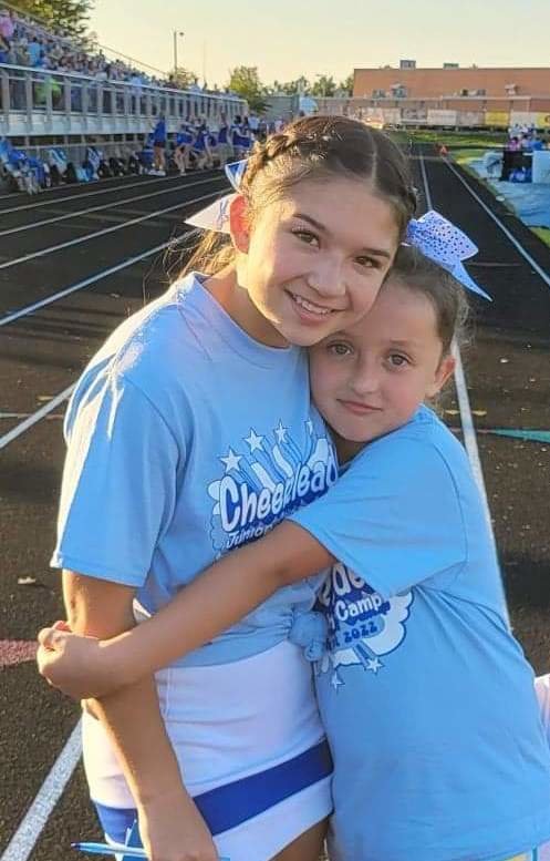 Junior cheerleader, Arya embraces her mentor after performing the pre-game show for Marshfield&rsquo;s Youth Night on Sept. 9.
