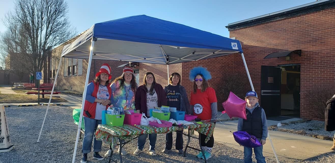 1st grade teacher Pam Earls, Para Andrea Long, 1st grade teacher Sarah Tucker, 3rd grade teacher Patricia Throne, 2nd grade teacher Heather Lewis and her son Cole pass out a free book to every student PK-5th grade.