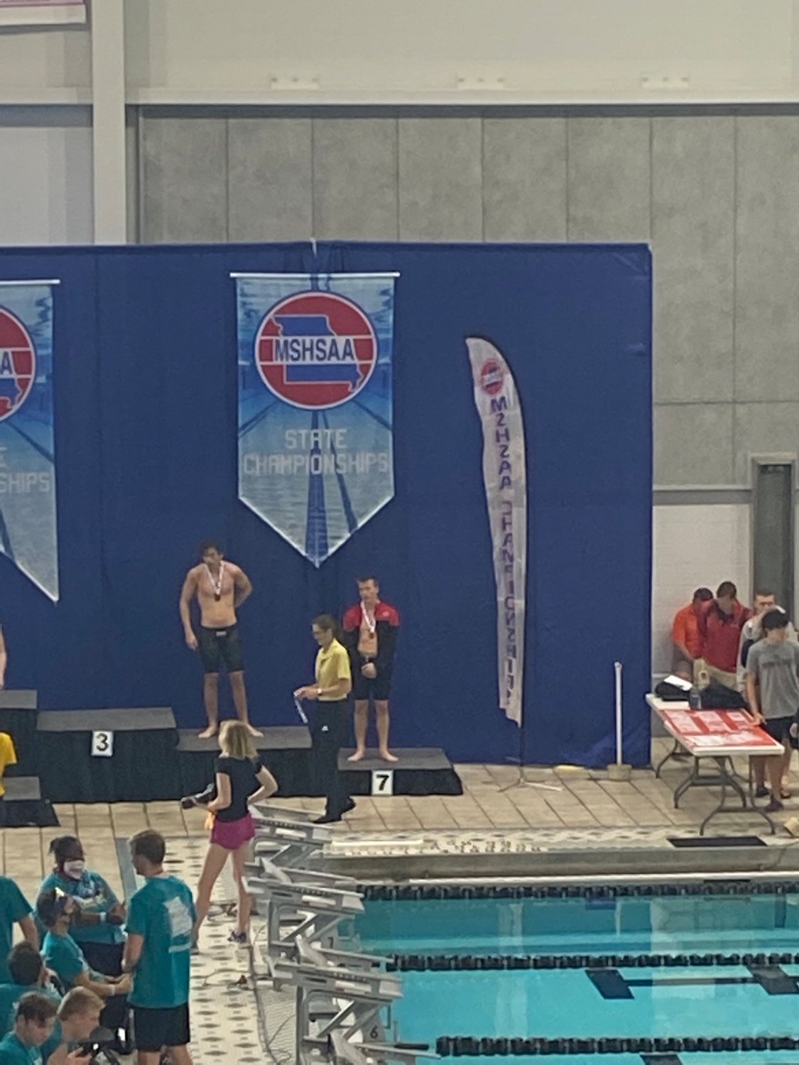 Caden Hendee standing on the 5th place podium. Hendee finished his high school career with two state medals and finished second in the consolation of the 50 yard freestyle with a time of 22.08, earning all state honors.