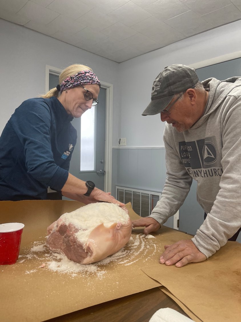 Laurie and Mike Vestal take time applying the cure which will preserve the ham over the next few months.