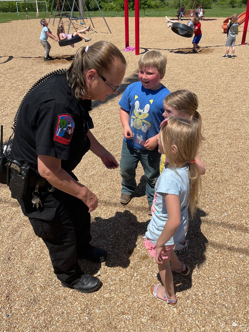 Kids gather round Officer Deckard to show her a cool coin, ask questions and give hugs.