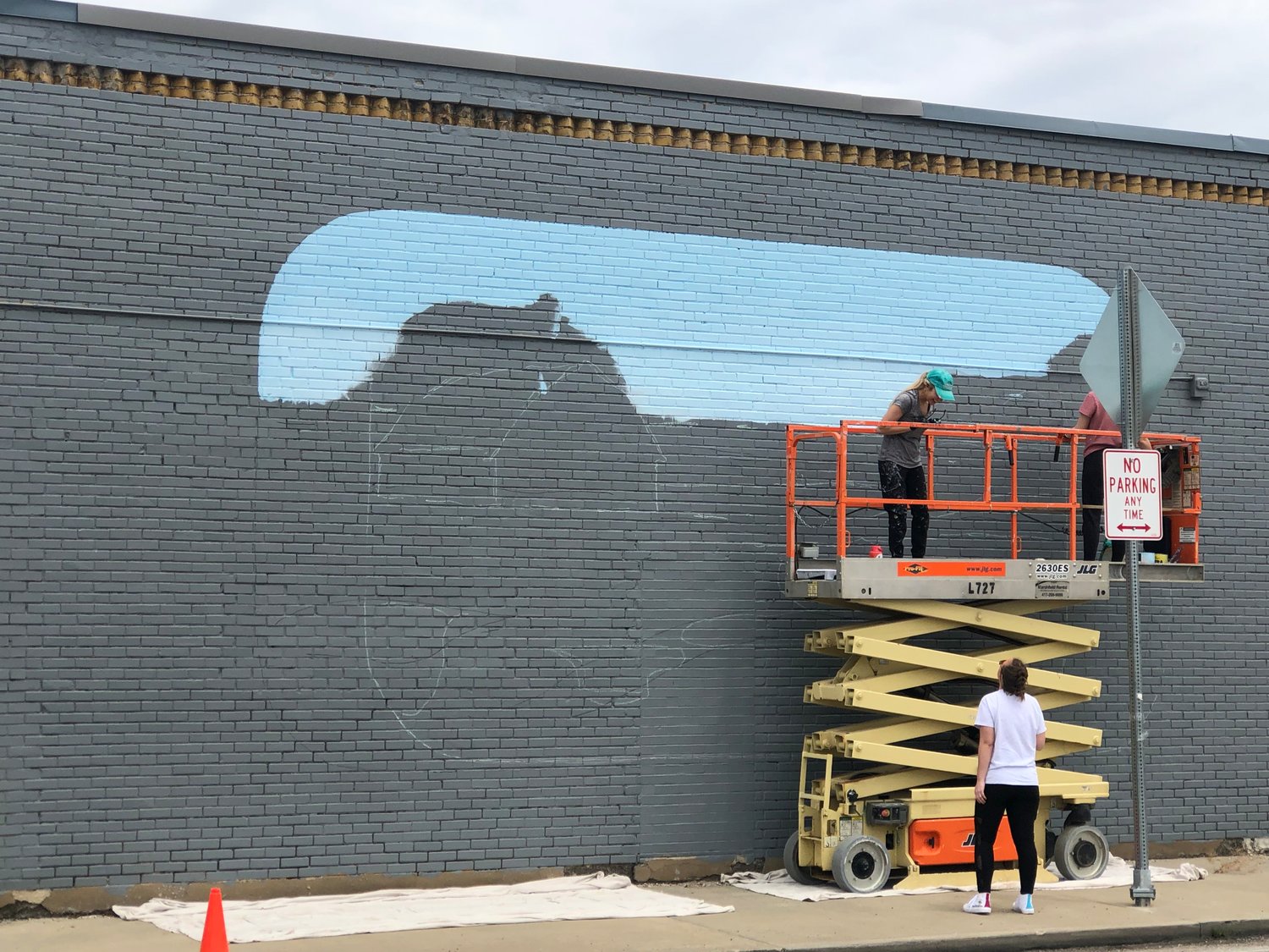 Samantha Cox pictured working on a “surprise” mural located at the four-way intersection of  E. Jackson St. and S. Crittenden.