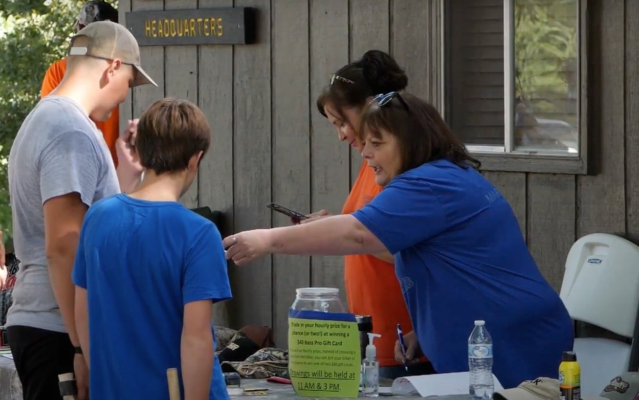Becca Hungerford (blue) and Toni Cline Lorenz (Orange) are both members of the First Baptist Church in Marshfield and are seen helping some participants enter a drawing for a BassPro Shops.