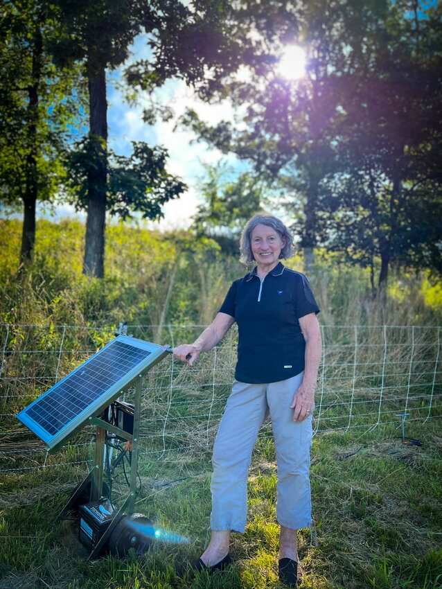 Here we see Justin Trails business owner, Donna Justin, with a sunny oak savanna backdrop, which is made possible by dedication and hard work by her late husband Don, herself, and many helpers, over the past twenty years. Conservation was included in their business model. Evident in this photo is Donna’s deep and humble joy, her love for the land, and how she is literally in touch with the latest in technology and innovation. Here, with a small solar panel to run the Goats on the Go electric fence.