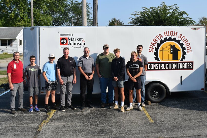 Representatives from Market and Johnson company, teachers, and students assemble for the dedication of the project trailer donated by Market and Johnson. From left to right, we have Instructor - Steve Schauf, Nicholas Lueth (Sr), Anna Osmond (Jr), Mike Seichter (M&J), Craig Namyst (M&J), Carter Olson (Jr) Milo Riley (Jr), Reese Ott (Sr) and Instructor Mitchell Roberge.