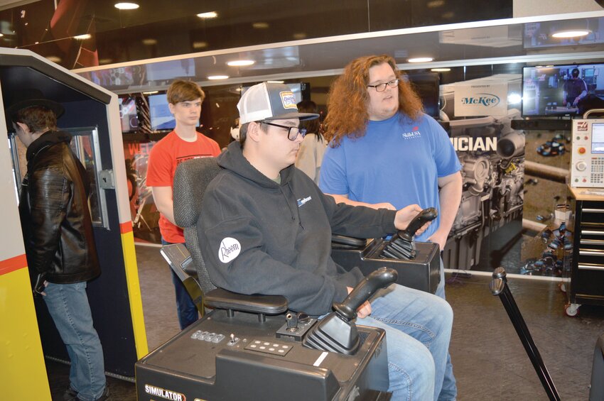 Huntsville sophomore Blake Cline tries out a backhoe simulator with Skills USA student instructor Jordan Grover, a senior, guiding him as sophomore Dominic Davis watches during a tour of the &ldquo;Be Pro, Be Proud&rdquo; mobile workshop housed in a semitruck. The Career Technical Education complex hosted the event on March 12.