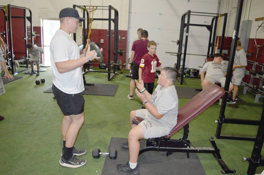 Assistant coach Knox Laird works with football players in the weightroom.