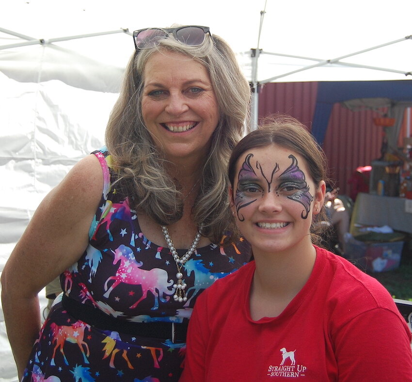 Face painter Tammy Scholz, of Jasper, left, gets approval of her work by Myleigh Ricketts of Mt. Judea at the Newton County Homecoming Shindig. Face painting was offered at the booth operated by The Learning Center of North Arkansas which is in the process of opening a new facility in Jasper.