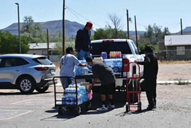 Community members unload donations of water and other drinks at Burdette Hall, San Carlos.