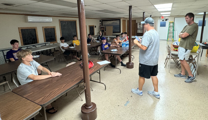 Holy Cross eighth grade basketball coaches Luke Tillman, right, and Aaron Eddy, second from right, told the team it was chosen to lead the 2024 Mendota Sweet Corn Festival Parade as the grand marshals at a special pizza party just for the announcement on July 8 at Holy Cross. (Reporter photo by Brandon LaChance)