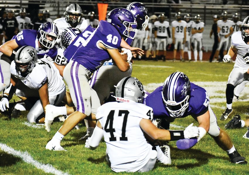 Junior Roman Villalobos runs through the line of scrimmage as senior Kaiden Morris (right) finishes a block during the Rochelle Hub varsity football game against Kaneland on Friday.