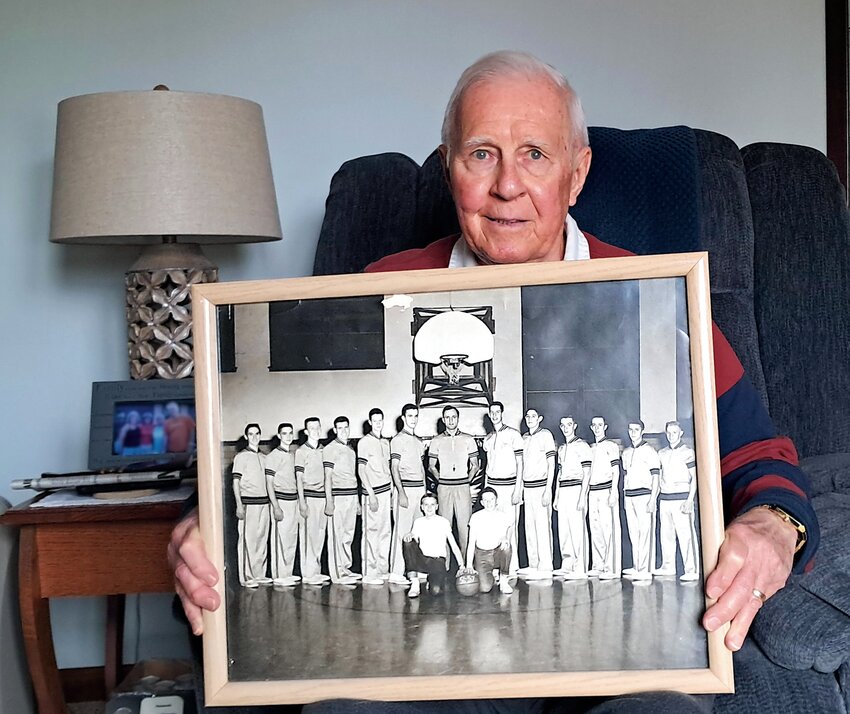 Rex Bell holds a team photo from his 1956-57 Clinton Maroons basketball team.  Bell is pictured standing second from the right.