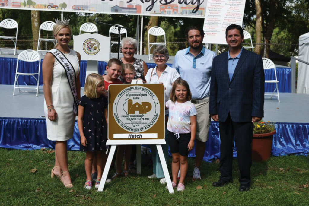 Pictured from left to right, Kelsi Kessler, Miss IL County Fair Queen, Maxine Grossmann (peering at the sign), Luke Grossmann, Charlotte Grossmann, Heidi Palmer (behind Charlotte), Amy Palmer, Millie Grossmann, Dalton Grossman, and Jerry Costello II, Illinois Director of Agriculture.
Photo submitted