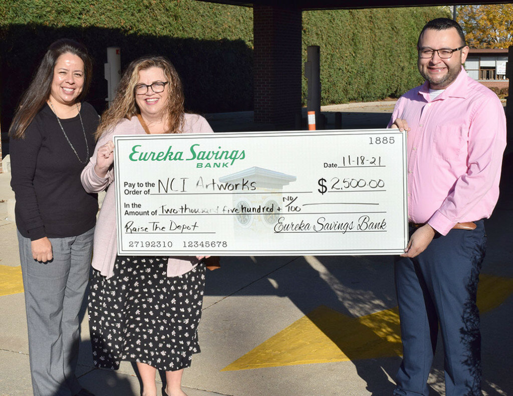 Anna Arteaga, left, and Jesse Arellano, right, of Eureka Savings Bank in Mendota, present a check for $2,500 from the bank to Michelle Wade, who is spearheading the fundraising effort for the “Raise the Depot” project in Mendota. (Reporter photo)