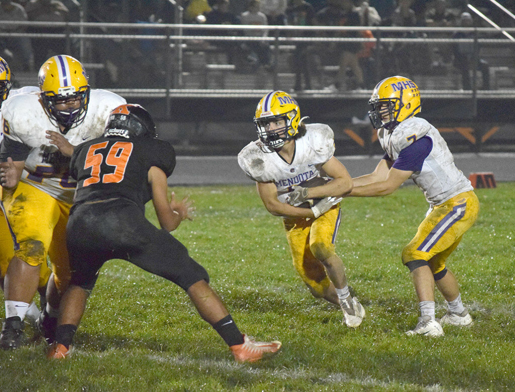Mendota’s Anthony Childs takes a handoff from Ted Landgraf and looks for running room while Trojan lineman Jordan Coney, left, supplies a block on Oct. 8 at Kewanee. (Reporter photo)