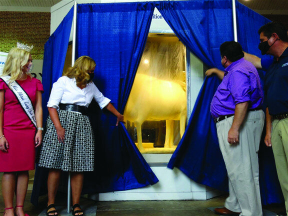 Gov. JB Pritzker and First Lady MK Pritzker unveil the Illinois State Fair’s 2021 butter cow, along with Department of Agriculture Director Jerry Costello II, far right, and 2021 Miss Illinois County Fair Queen Kelsi Kessler. This year’s sculpture, by artist Sarah Pratt, is entitled “Embracing Tradition.” It contains 13 hidden hearts that signify the 13 essential nutrients that occur naturally in milk. (Capitol News Illinois photo by Peter Hancock)
