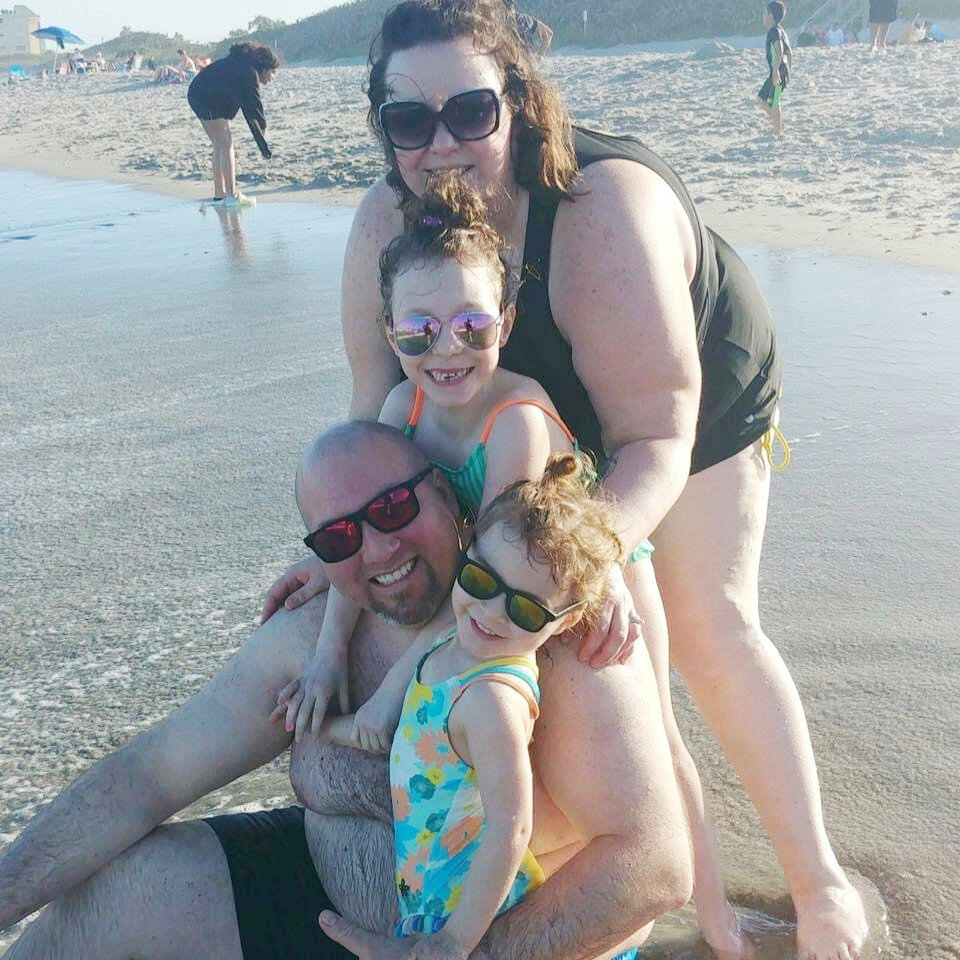 A recent photo of Gabrielle and Derek Troha on the beach with their daughters, Lilly and Lana.