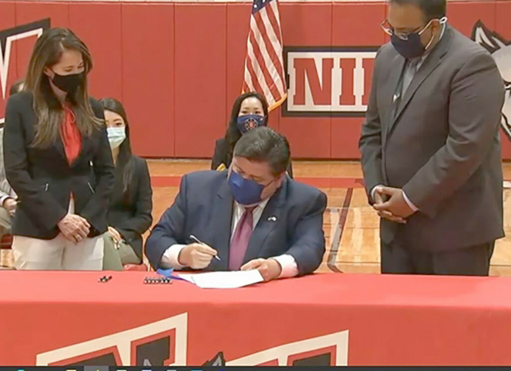 Gov. JB Pritzker signs a bill into law on July 9 requiring all public schools in Illinois to teach a unit of Asian American history, starting in the 2022-2023 school year as the bill's sponsors, Rep. Jennifer Gong-Gershowitz, left, and Sen. Ram Villivalam look on. (Credit: Blueroomstream.com)