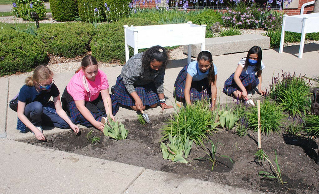 Fifth grade students from Holy Cross School in Mendota plant a Pollinator Pocket garden near the entrance to Graves-Hume Public Library on May 14. Doing their part to help the pollinators of the world, left to right, are Kaylee MacDonald, Ashlynn Rickels, Giselle Gonzalez, Hayley Diaz and Gaby Martinez. (Reporter photo)