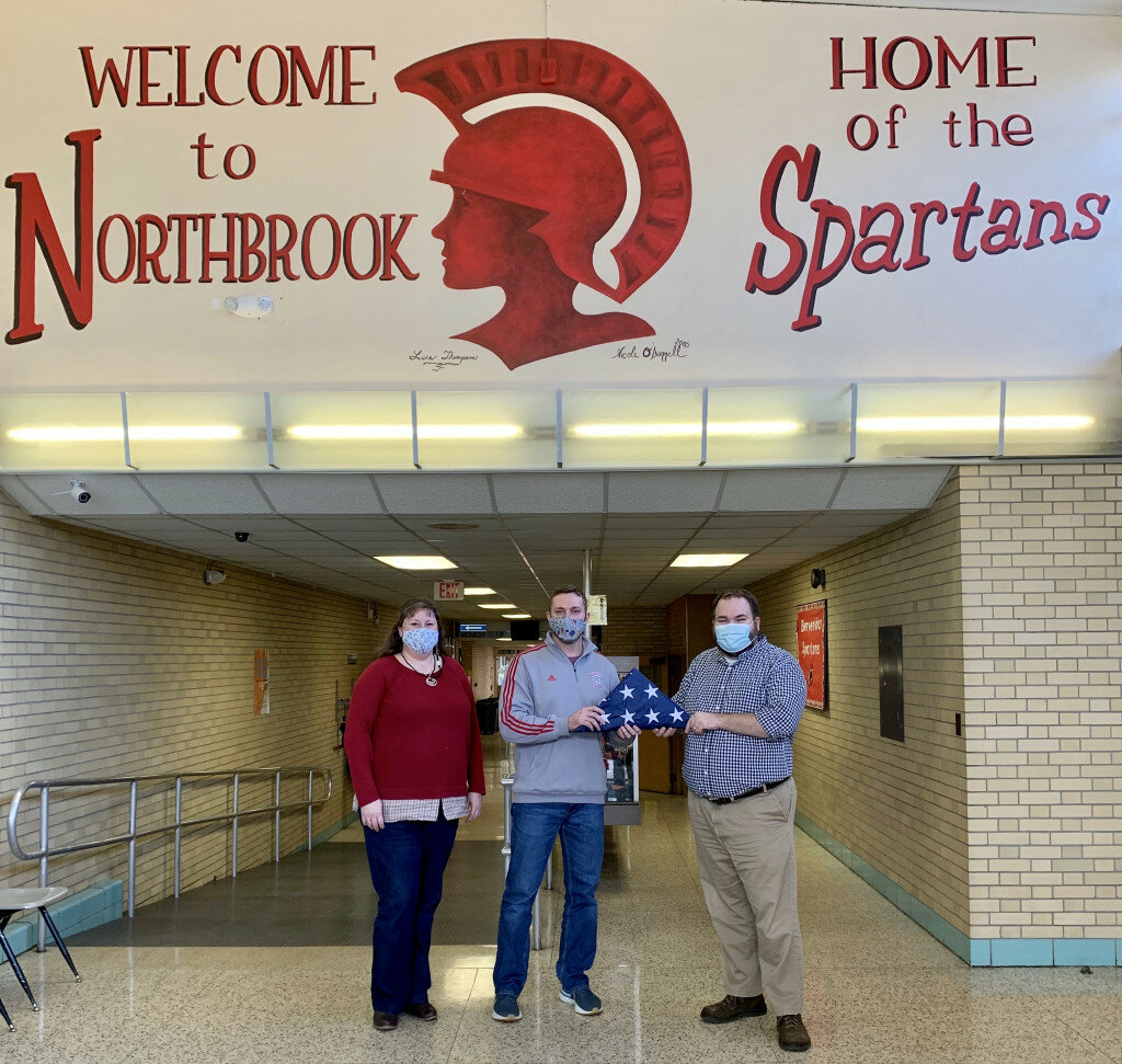 Tyler Pearce, Northbrook assistant principal, right, accepts a flag from Rachel Sabin, MEA president, left, and Brandon Scheppers, MEA member. The donation is a tribute to former longtime Mendota teacher Winnie Lovgren. (Photo contributed)