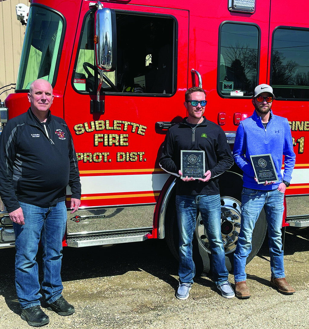 Sublette residents Nick Wilson, center, and Curtis Ryan Kessel, right, are presented with plaques by Sublette Fire Chief Kevin Schultz for their efforts in rescuing a child from a house fire in Sublette on March 14. (Reporter photo by Tonja Greenfield)