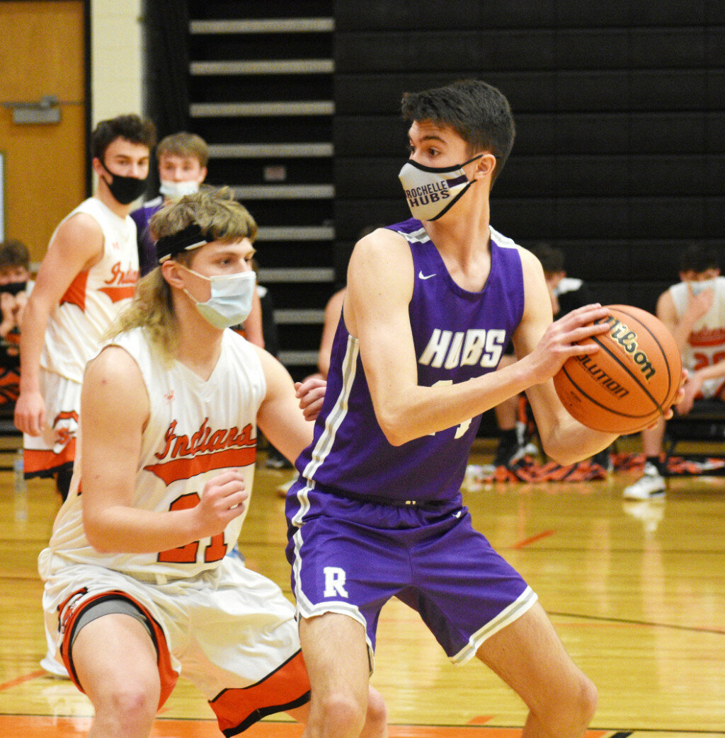 Junior Ryan Simmons protects the ball from Sandwich's Evan Wilson during the Rochelle Hub varsity basketball game against the Indians on Friday. (Photo by Russell Hodges)