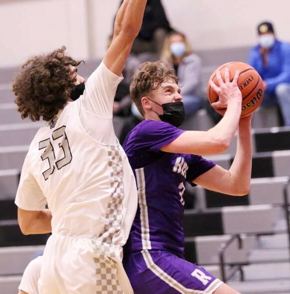 Senior Garrett Burdin drives between two Kaneland defenders during the Rochelle Hub varsity basketball game against the Knights on Saturday. Burdin scored 15 points in the game. (Photo by Marcy DeLille)