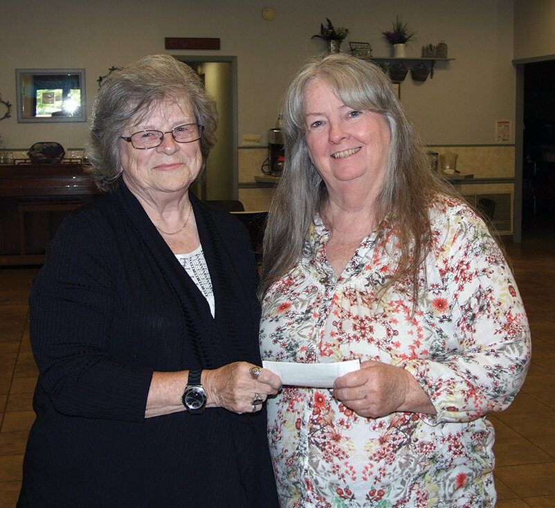 Gordon Woods / Journal — 
Margaret Feaman, president of the Clinton American Legion Auxilary, left, presents a $1,400 donation to Paula Jiles, executive director of the DeWitt County Friendship Center.  For several years, the Legion Auxiliary has baked cinnamon rolls as a community service for donations.  They took orders in advance and then delivered them the next day. This year, they baked 40 dozen.  Past recipients of the fundraiser has included Children’s Books for Summer, The Vault, HOOAH and Land of Lincoln Honor Flight.  This year, the Friendship Center was chosen to receive the proceeds from the annual baking project.  Feaman thanked everyone who helped and made donations.