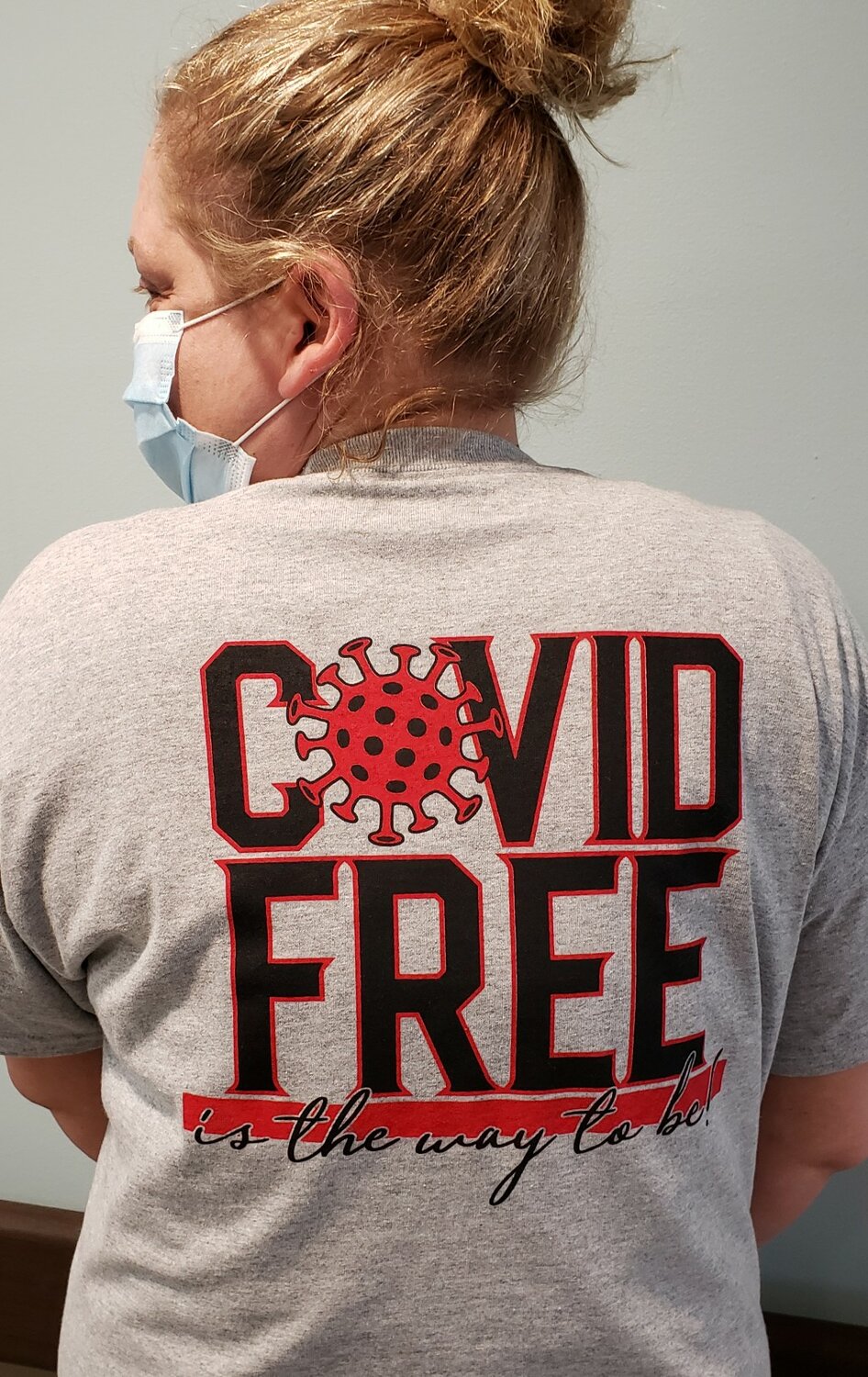 Jamie Faber, a CNA shower assistant at the Franklin Grove Living and Rehabilitation Center, shows off the back of the t-shirt that reads “Covid Free is the way to be.”