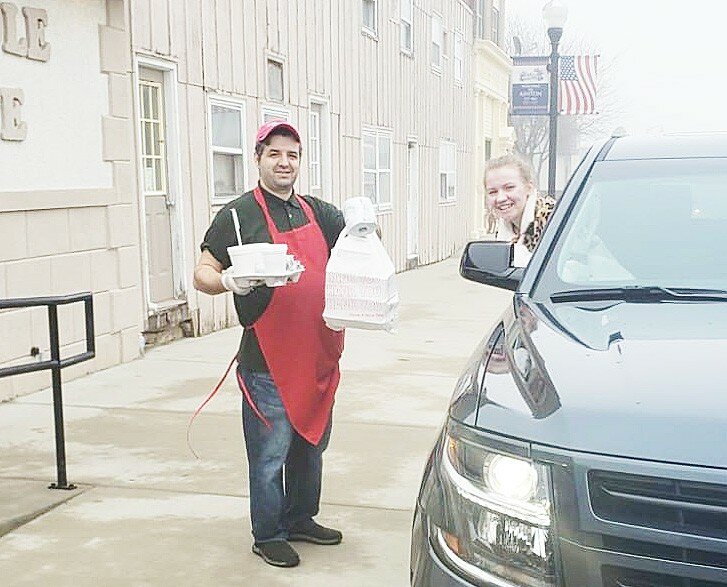 Mallory Henert picks up her curbside order Thursday at the Huddle Cafe in Ashton. Her order of two meals came with a free roll of toliet paper.