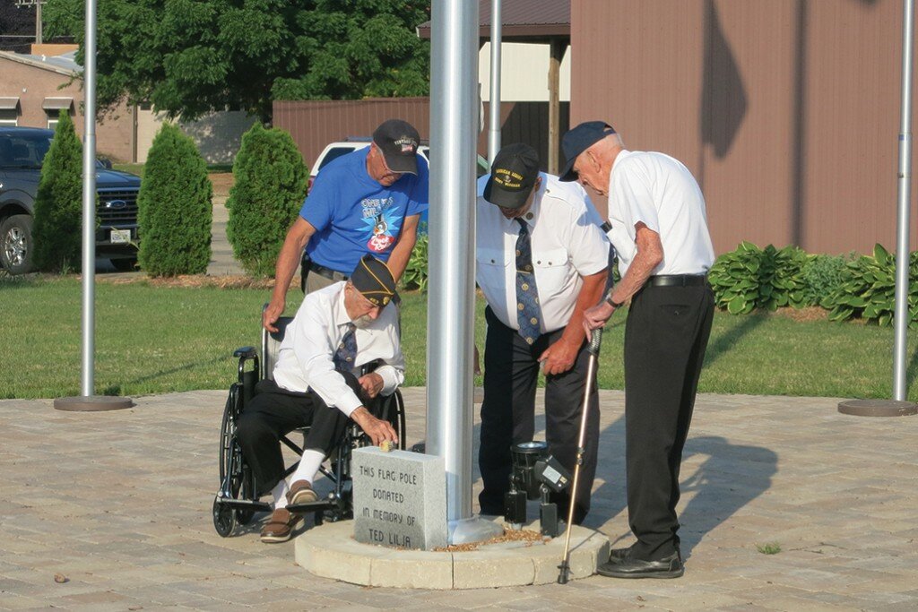 Pictured left, Amboy American Legion Commander Jack Mead and Jim Fredenhagen assisted World War II Veterans Walter “Ted” Fredenhagen, U.S. Marine Corps, and George Mason, U.S. Army-Air Force, as each poured sand from Omaha Beach, Normandy, France, at the base of the flagpole to honor those that served during World War II. 
Mary Mays/Amboy News